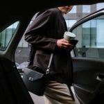 woman in black coat holding white ceramic mug